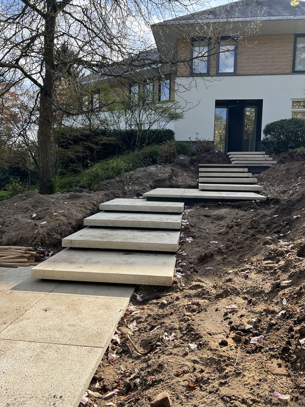 Betontegels en traptreden van Schellevis in een voortuin op afschot