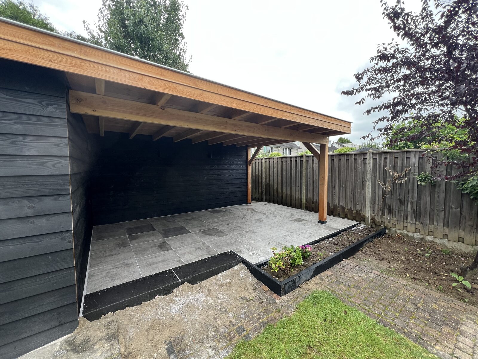 Douglas overkapping met zwarte wand en keramisch terras