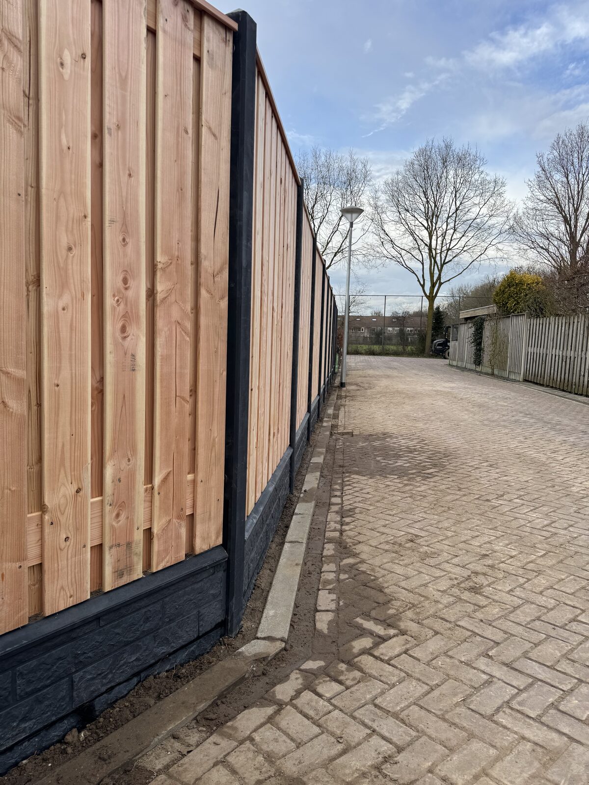 Hoge schutting langs een achterpad